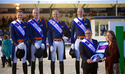 The Dutch team celebrate victory in the third leg of the FEI Nations Cup™ Dressage 2015 pilot series in Rotterdam, The Netherlands (L to R): Edward Gal, Diederik van Silfhout, Patrick van der Meer and Hans Peter Minderhoud. Dutch Chef d’Equipe, Wim Ernes, accepts the trophy from Show President, Belle de Bruin. Photo by FEI/Arnd Bronkhorst