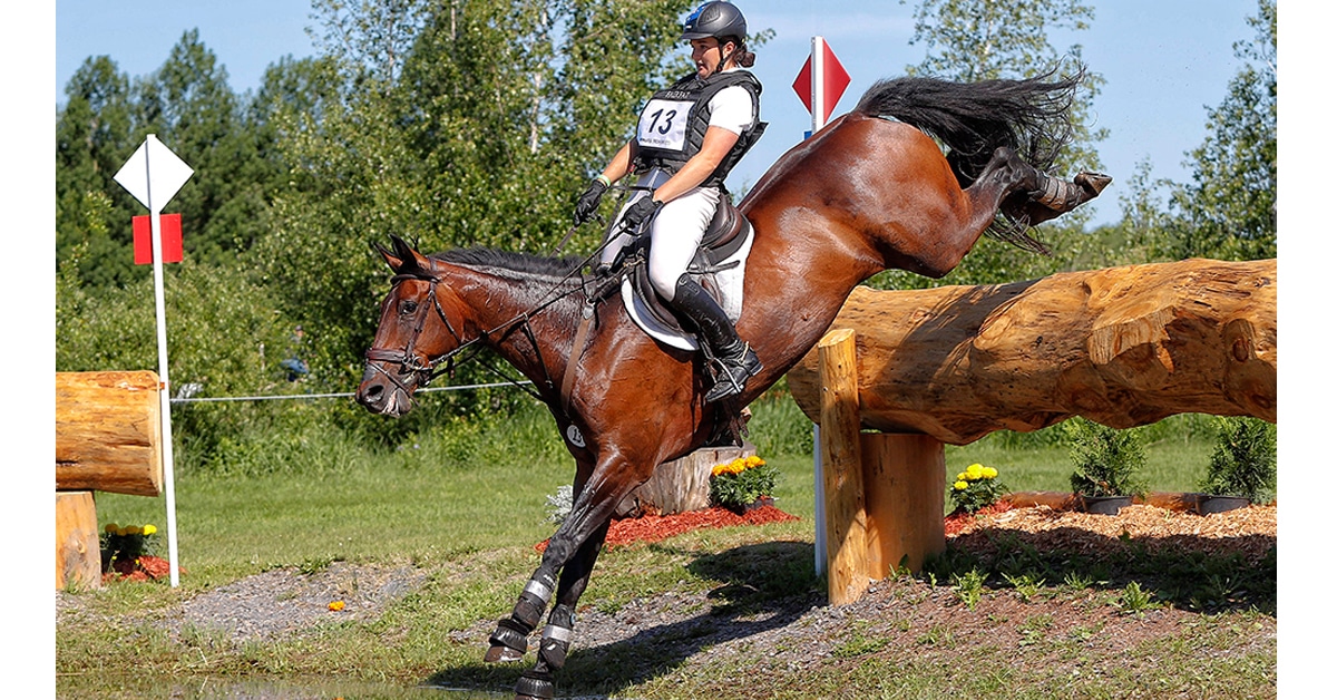 A horse and rider jumping over a log into the water at Bromont.