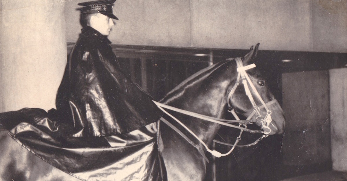 A black-and-white photo of a mounted policeman on a horse.