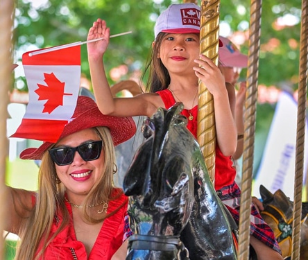 Mother and daughter on a carousel with Canadian flag.