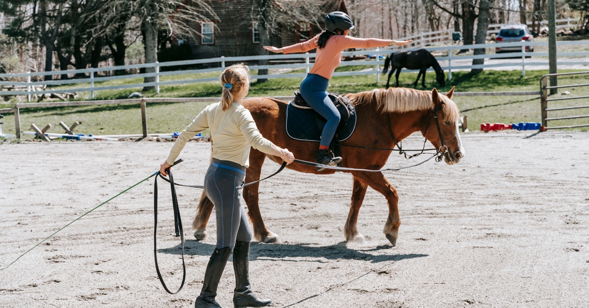 A coach lungeing a child on a horse.