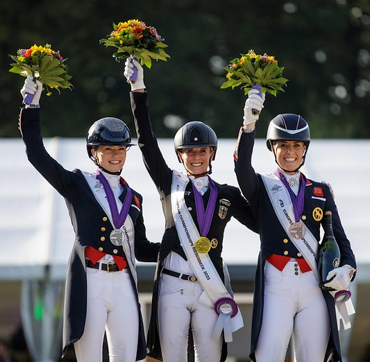 Three women with flowers on a podium.