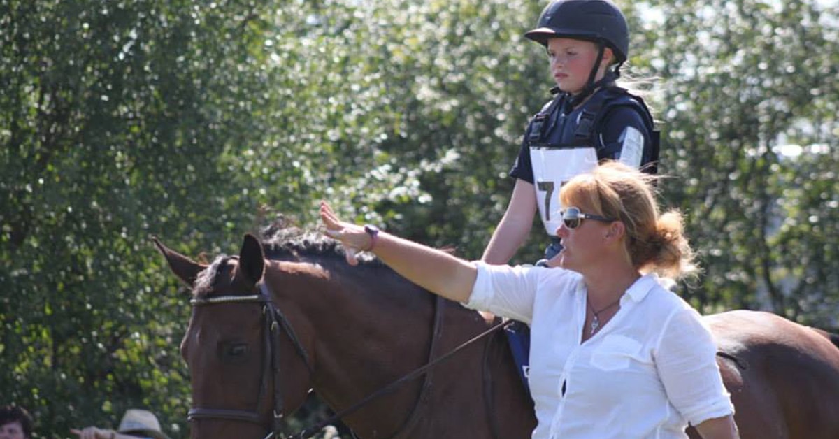 A woman coaching a young rider on a horse.