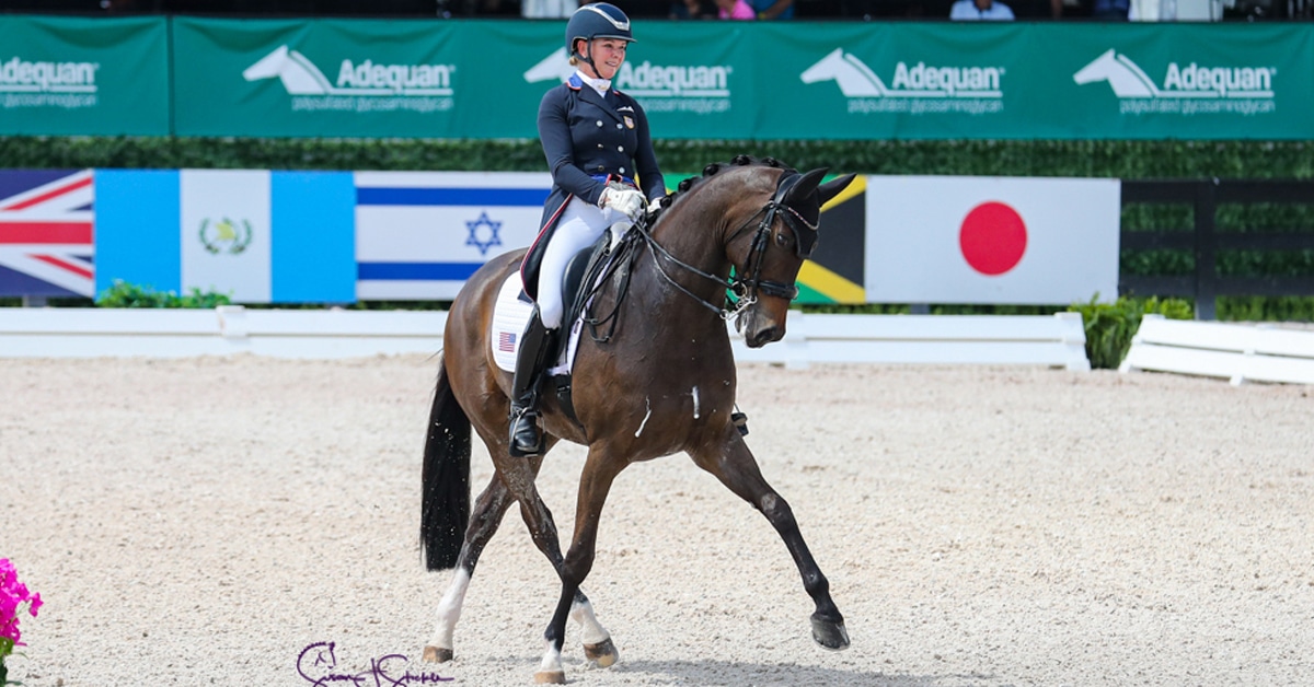 A woman and bay horse performing a half-pass in a dressage arena.