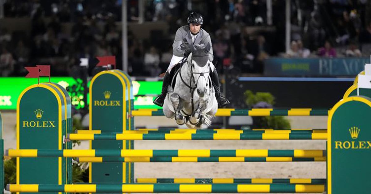 A grey horse and rider jumping a Rolex fence at WEF.
