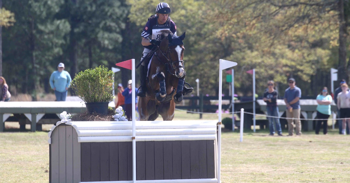 A horse and rider jumping a cross-country fence at Stable View.