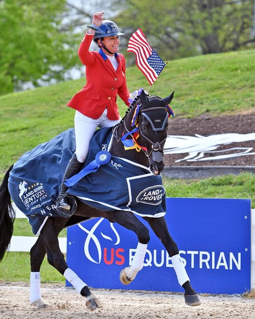A woman on a black horse waving a flag during the victory gallop.