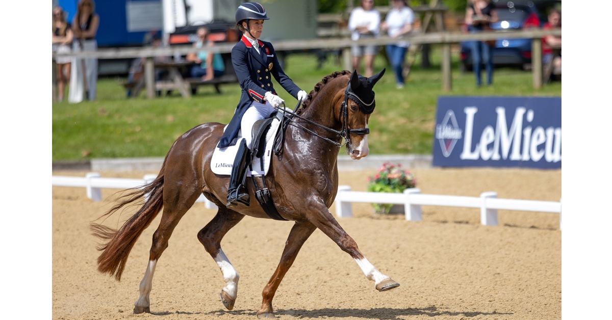 A woman riding a dressage horse at extended trot in competition in England.