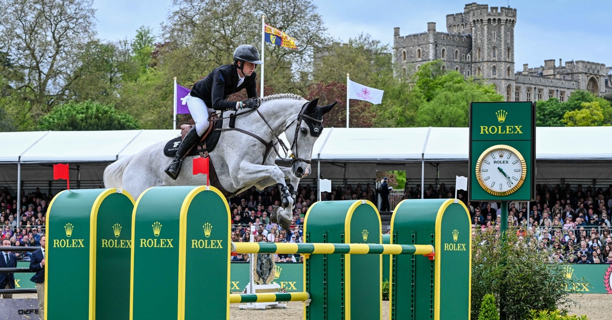 A man and grey hotse jumping a fence at Windsor.