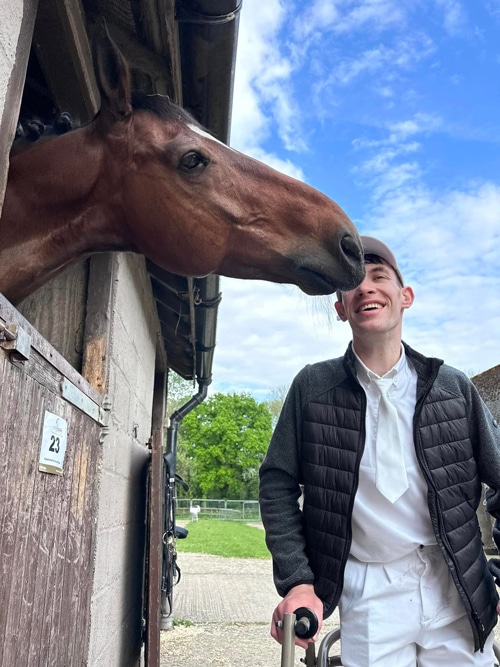 A bay horse sniffing a smiling man.