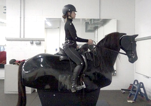 A woman riding a mechanical horse.