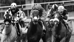 Black-and-white image of horses racing.