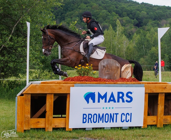 A horse and rider jumping a cross-country fence at Bromont.