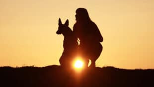 A woman and dog at sunset.