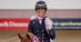 A dressage rider holding up a medal.