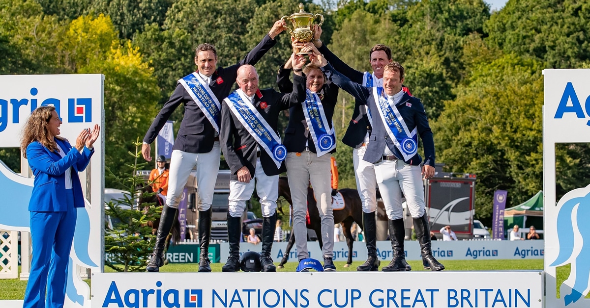 A group of riders hoisting a cup on a podium.